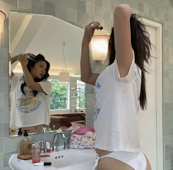 Азиатка в белых трусиках делает макияж перед зеркалом