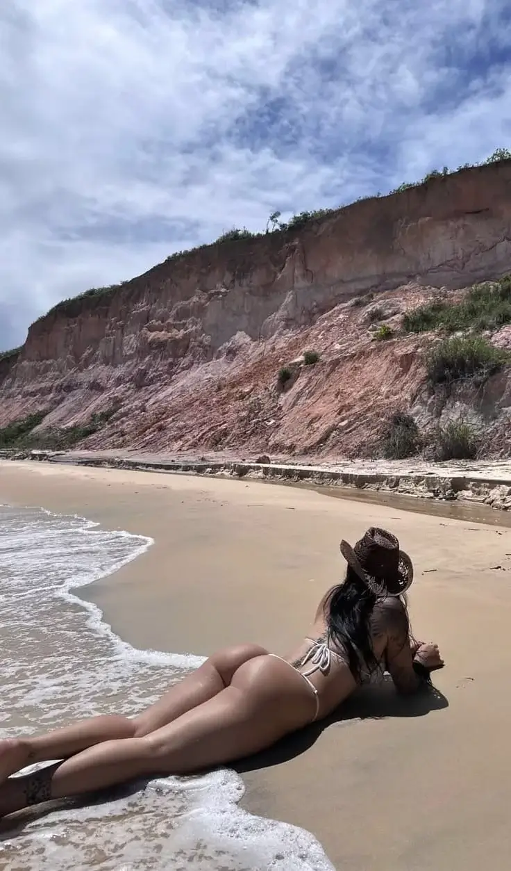 Брюнетка в шляпе греет попу под солнцем