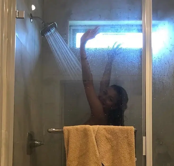 Девушка подняла руки и подставила грудь под струи воды в душе