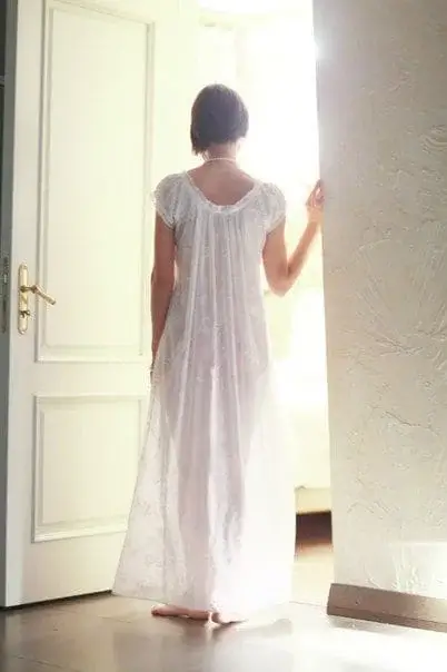 Девушка в ночном прозрачном пеньюаре заходит в спальню