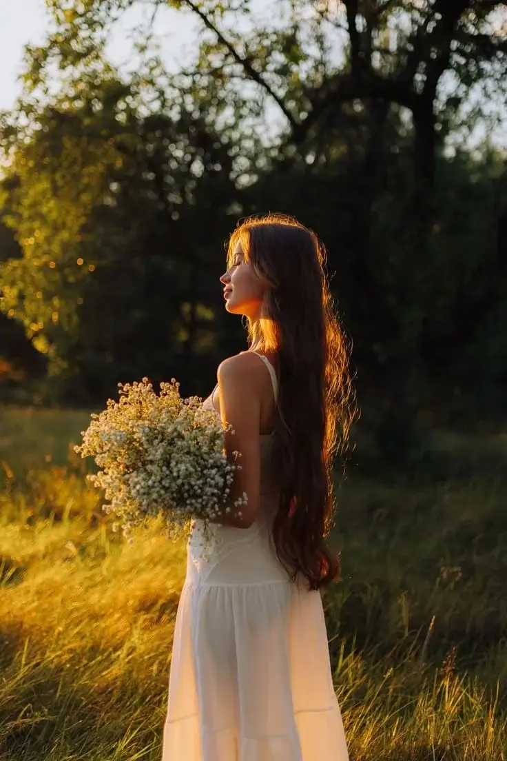Девушка в прозрачном белом платье и с букетом лесных цветов