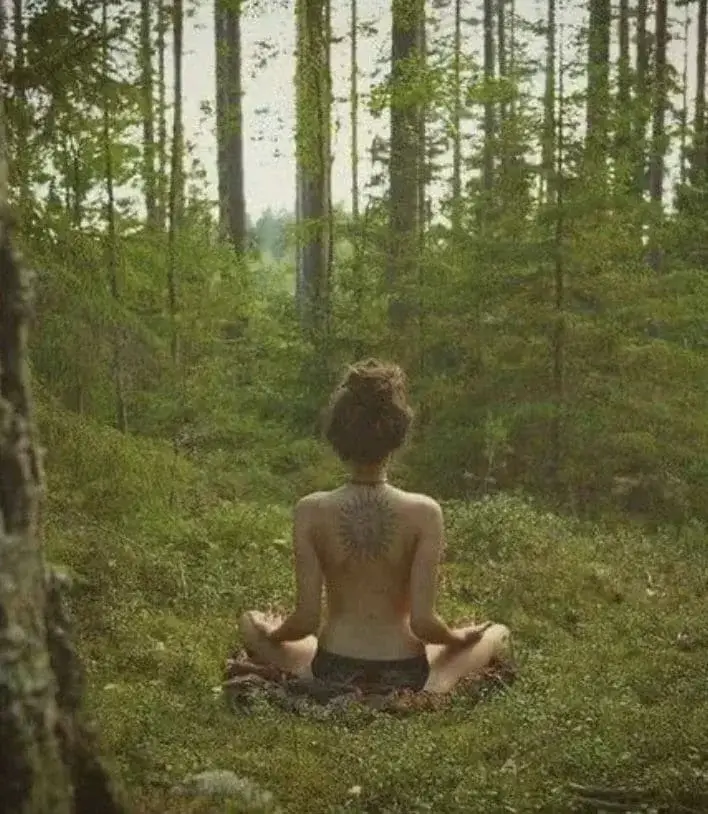 Девушка в трусиках медитирует на поляне в лесу