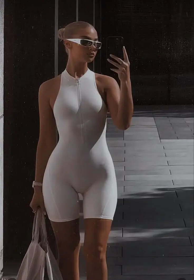 Шикарная блондинка в коротком белом комбинезоне в обтяжку